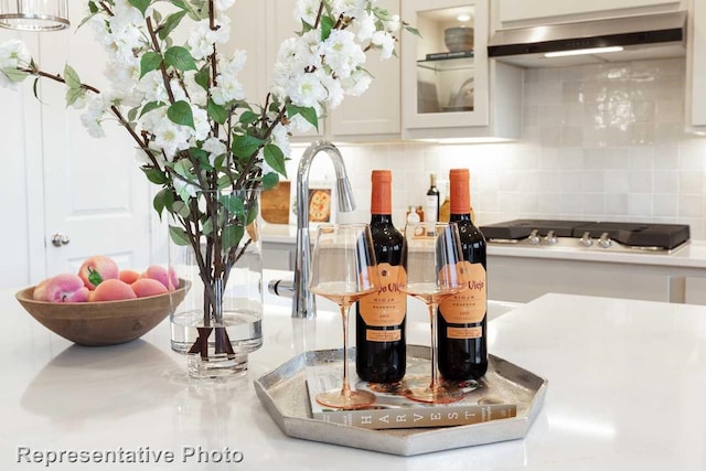 details with decorative backsplash, stainless steel gas stovetop, and white cabinets