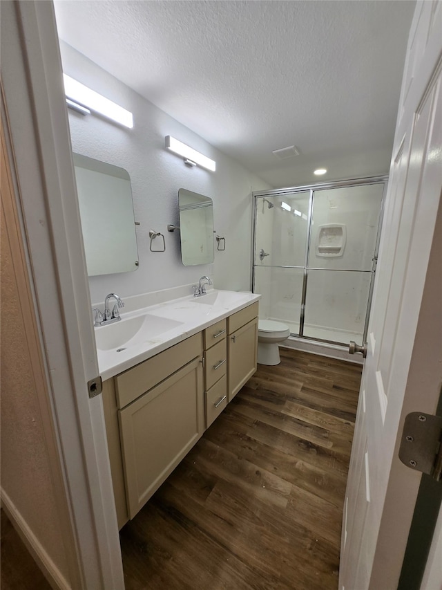 bathroom featuring toilet, an enclosed shower, a textured ceiling, vanity, and hardwood / wood-style flooring