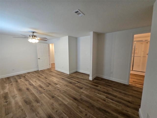 empty room with ceiling fan, dark hardwood / wood-style flooring, and a textured ceiling