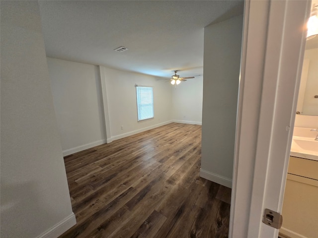 empty room featuring dark hardwood / wood-style flooring, sink, and ceiling fan