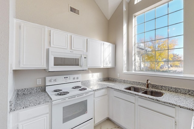 kitchen with white cabinets, plenty of natural light, and white appliances