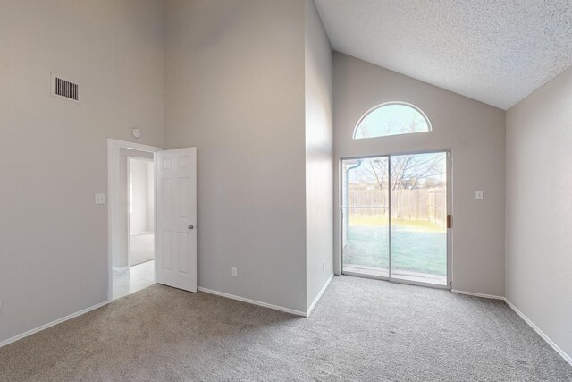 carpeted spare room with high vaulted ceiling and a textured ceiling