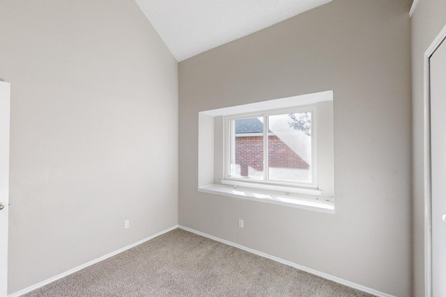 spare room featuring light colored carpet and vaulted ceiling