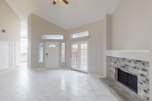 foyer with ceiling fan, high vaulted ceiling, and a brick fireplace