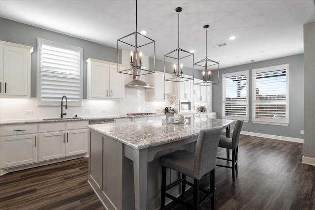 kitchen featuring visible vents, white cabinets, a center island, and a sink