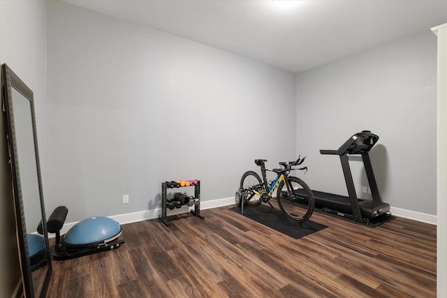 exercise room featuring dark wood finished floors and baseboards