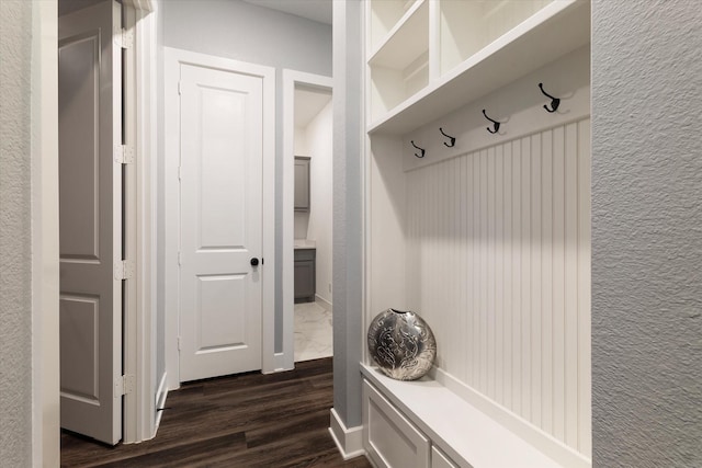 mudroom featuring dark wood-type flooring and a textured wall