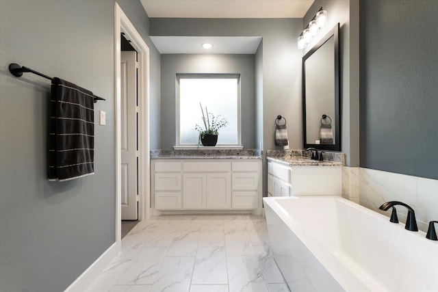 bathroom featuring baseboards, two vanities, a soaking tub, marble finish floor, and a sink