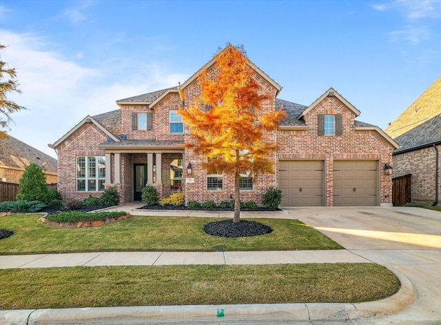 traditional-style home featuring brick siding, an attached garage, concrete driveway, and a front yard