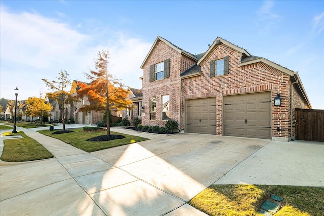 traditional-style home with driveway, brick siding, an attached garage, and fence