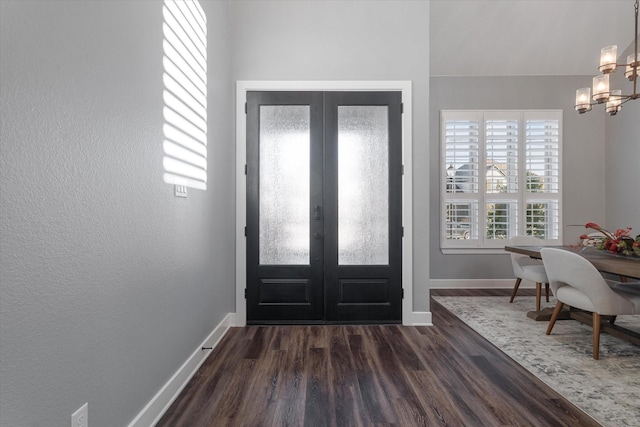 entrance foyer with french doors, baseboards, a notable chandelier, and dark wood finished floors