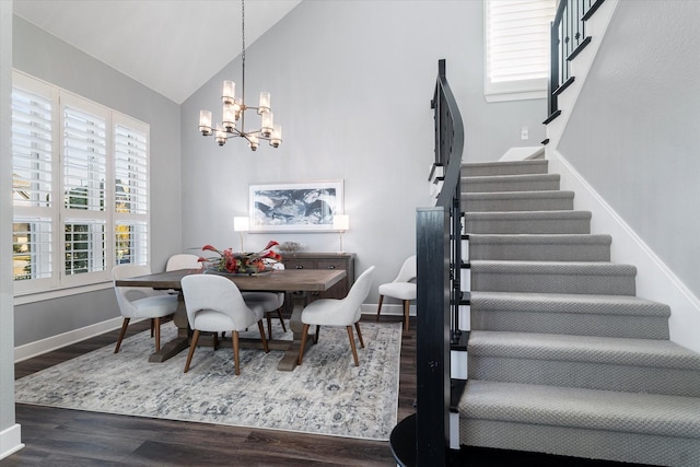 dining room with dark wood-type flooring, high vaulted ceiling, a notable chandelier, stairway, and baseboards