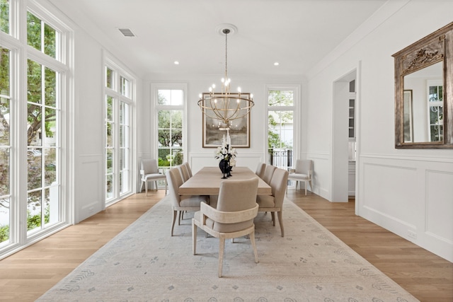 dining space with an inviting chandelier, light wood-type flooring, and ornamental molding