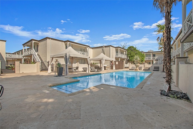 view of swimming pool with fence, stairs, a gazebo, a fenced in pool, and a patio area