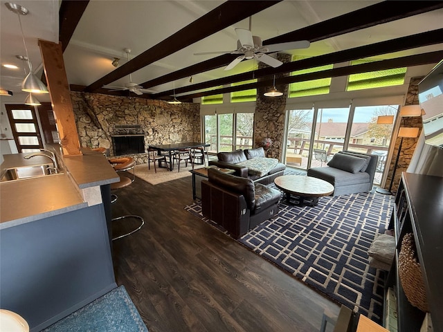 living room featuring sink, dark hardwood / wood-style floors, ceiling fan, a fireplace, and beam ceiling