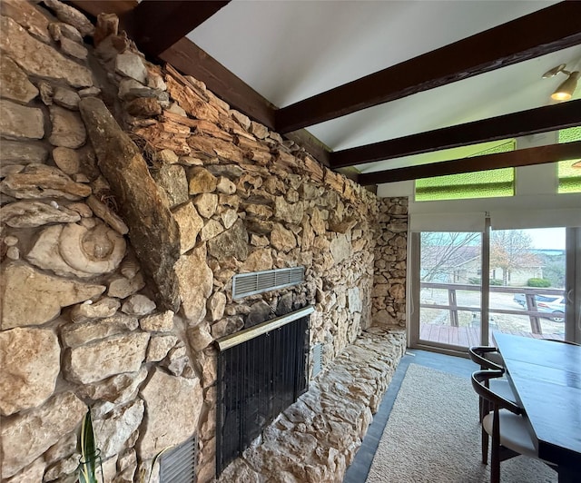 unfurnished living room with a stone fireplace and beamed ceiling