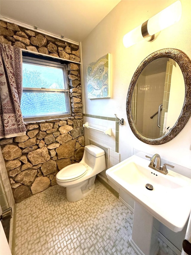 bathroom featuring sink, toilet, and tile walls