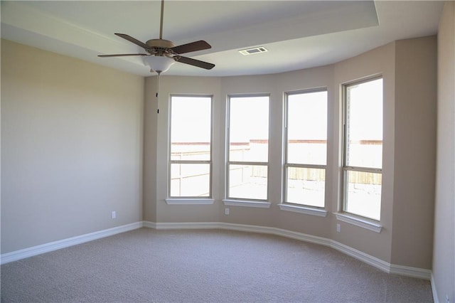 carpeted empty room with ceiling fan and a wealth of natural light