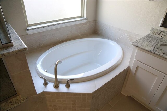 bathroom featuring vanity and tiled bath