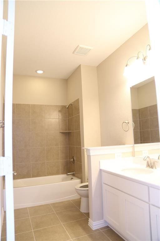 full bathroom featuring tiled shower / bath, vanity, toilet, and tile patterned flooring