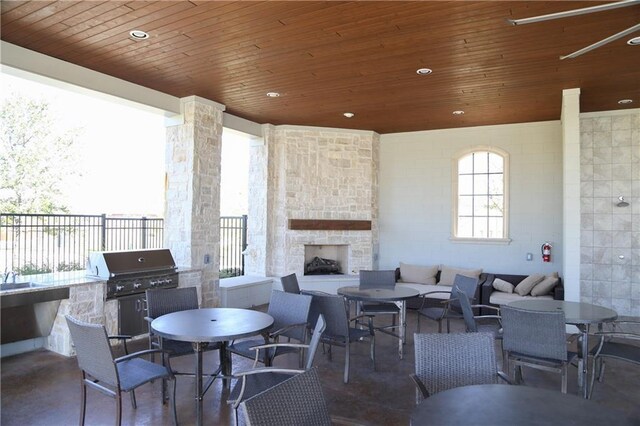 view of patio with an outdoor stone fireplace, an outdoor kitchen, ceiling fan, and a grill