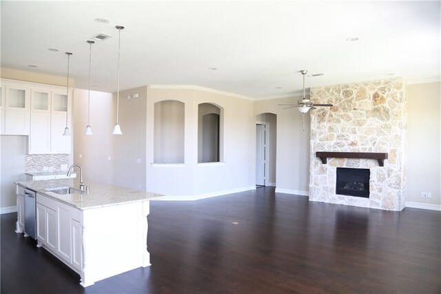 kitchen with sink, light stone counters, white cabinetry, and an island with sink