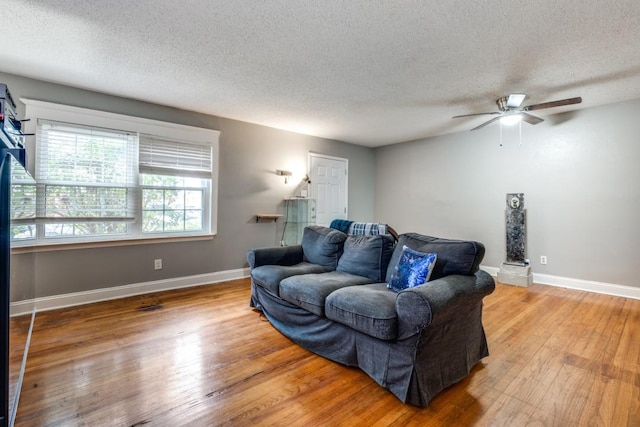 living room featuring a textured ceiling, ceiling fan, and wood-type flooring