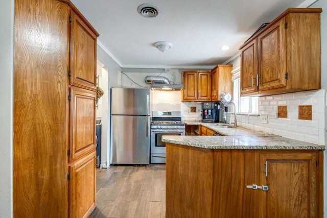 kitchen with sink, tasteful backsplash, light hardwood / wood-style floors, and appliances with stainless steel finishes