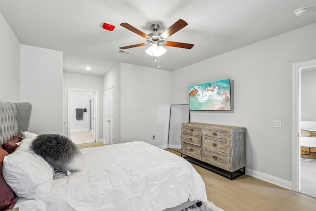 bedroom with ceiling fan, ensuite bathroom, and light hardwood / wood-style flooring