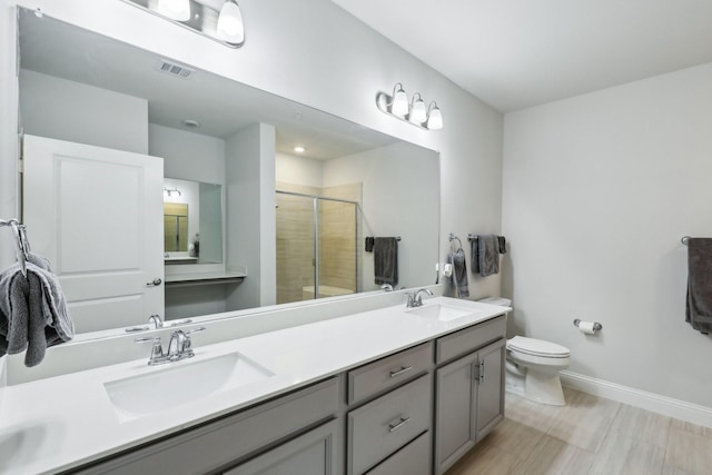 bathroom featuring a shower with shower door, toilet, and vanity