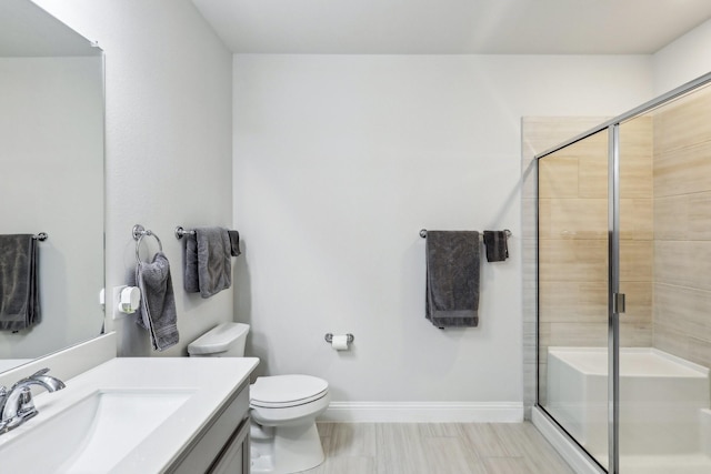 bathroom with toilet, vanity, and a shower with door