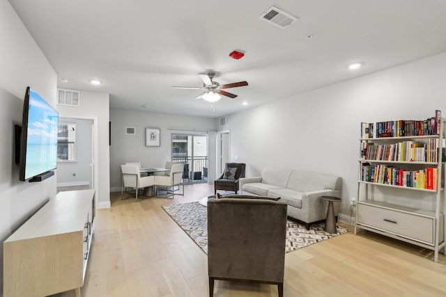 living room with light wood-type flooring, ceiling fan, and a wealth of natural light