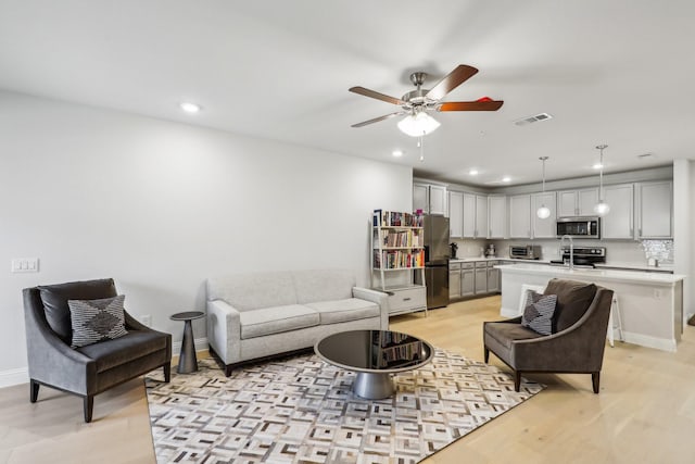 living room featuring ceiling fan and light hardwood / wood-style floors