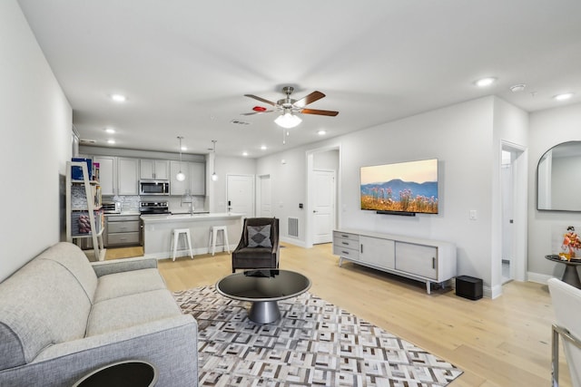 living room with ceiling fan, light hardwood / wood-style flooring, and sink