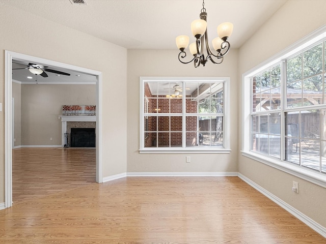 unfurnished dining area with ceiling fan with notable chandelier and light hardwood / wood-style floors