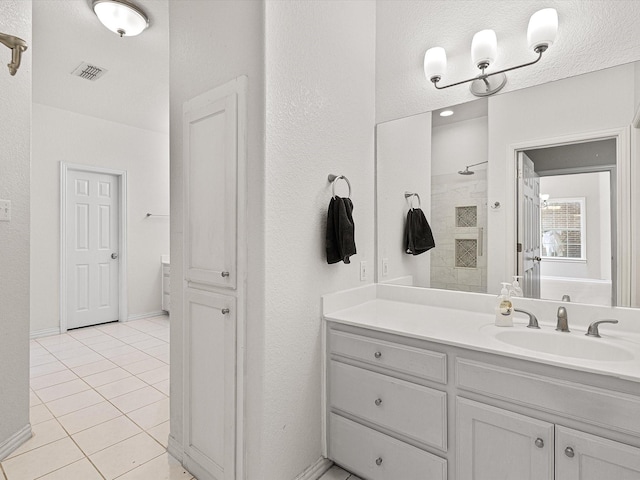 bathroom with a shower, vanity, and tile patterned flooring