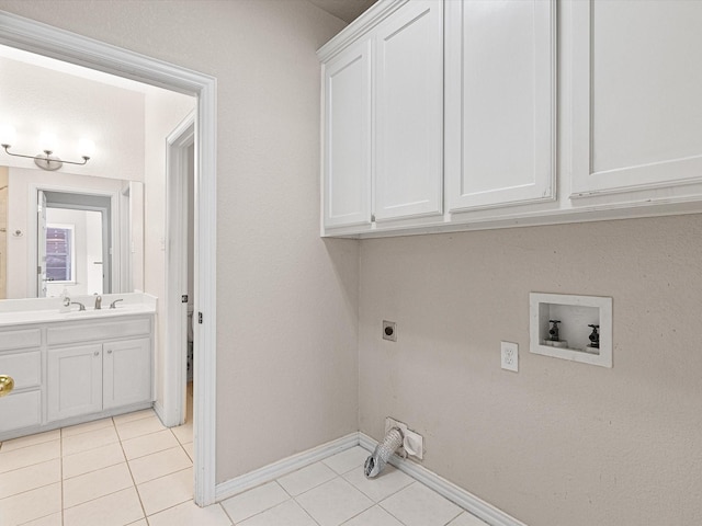 clothes washing area featuring electric dryer hookup, hookup for a washing machine, light tile patterned floors, and cabinets