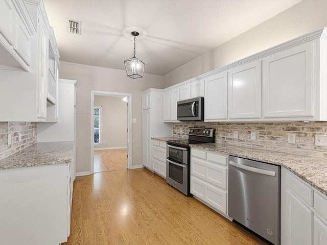 kitchen featuring pendant lighting, white cabinetry, appliances with stainless steel finishes, and tasteful backsplash