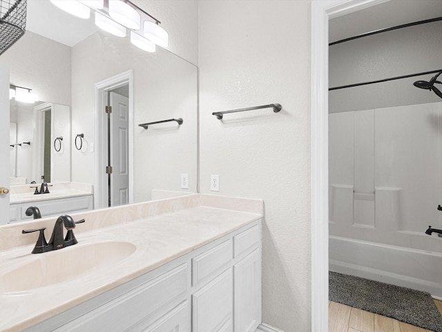 bathroom with washtub / shower combination, wood-type flooring, and vanity