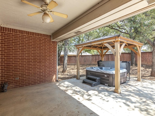 view of patio featuring a gazebo, ceiling fan, and a hot tub