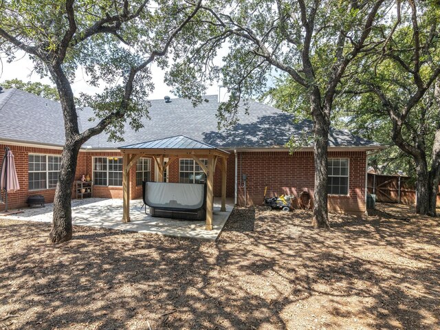 rear view of property featuring central air condition unit, a patio, and a hot tub