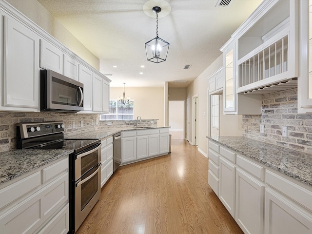 kitchen featuring pendant lighting, sink, white cabinets, light hardwood / wood-style floors, and stainless steel appliances