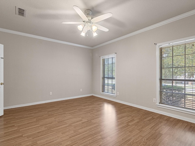 empty room featuring crown molding, plenty of natural light, and hardwood / wood-style flooring