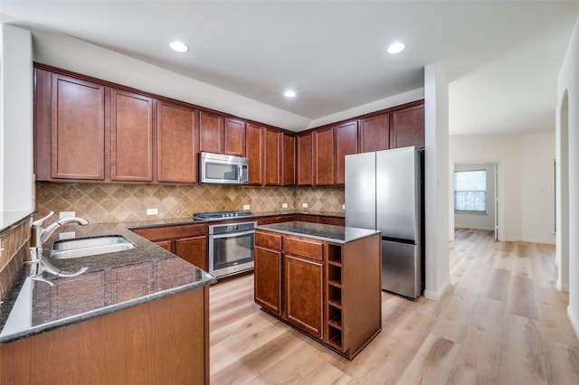 kitchen featuring dark stone counters, sink, light wood-type flooring, a kitchen island, and stainless steel appliances