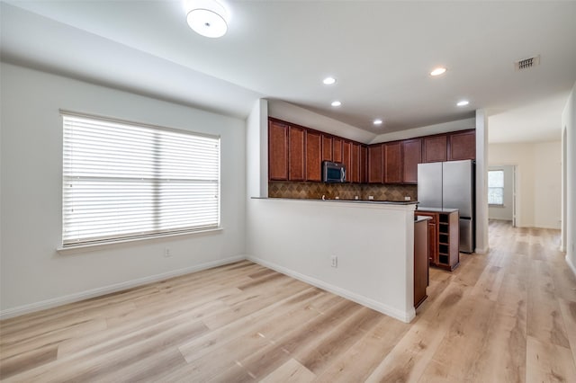 kitchen featuring decorative backsplash, kitchen peninsula, stainless steel appliances, and light hardwood / wood-style flooring