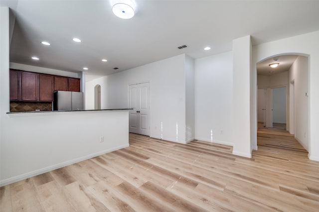 kitchen featuring stainless steel fridge, backsplash, and light hardwood / wood-style floors