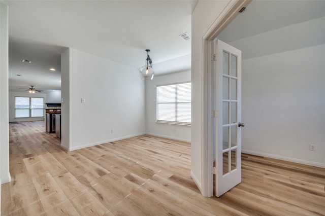 empty room with ceiling fan, french doors, and light wood-type flooring