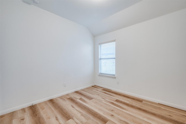 spare room featuring light hardwood / wood-style flooring and vaulted ceiling