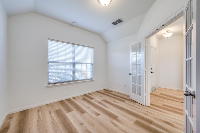 empty room with lofted ceiling, french doors, and light hardwood / wood-style flooring