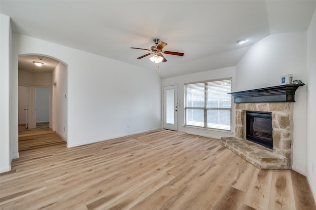 unfurnished living room with a fireplace, light wood-type flooring, vaulted ceiling, and ceiling fan